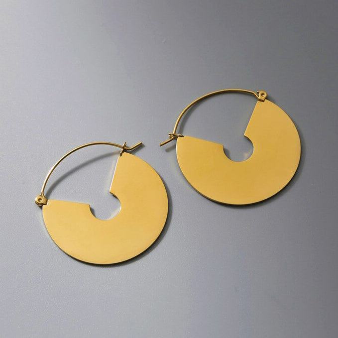 Gold Smooth Fan Drop Earrings shining brilliantly on a plain grey background.