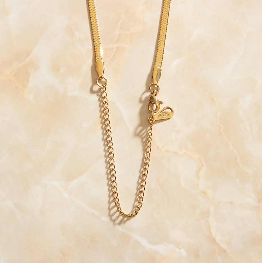 The back end of a Gold Snake Chain Necklace showing the clip attachment and extension chain.