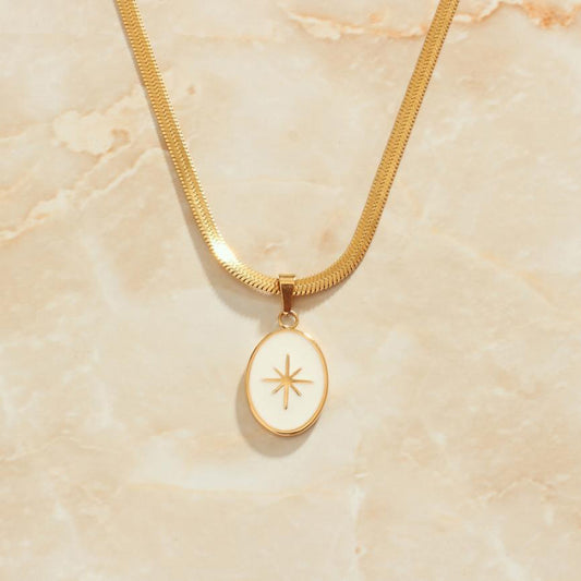 A gold snake chain necklace with a star pendant hanging.