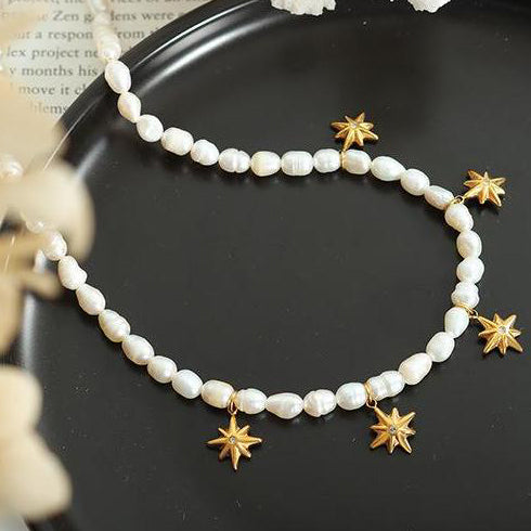 Closeup shot of the Gold Star Charm Necklace laying on a black dish.