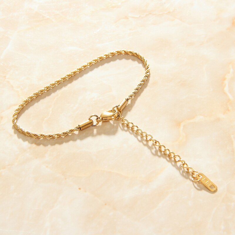 Gold Thin Rope Chain Link Bracelet on a smooth marble background.