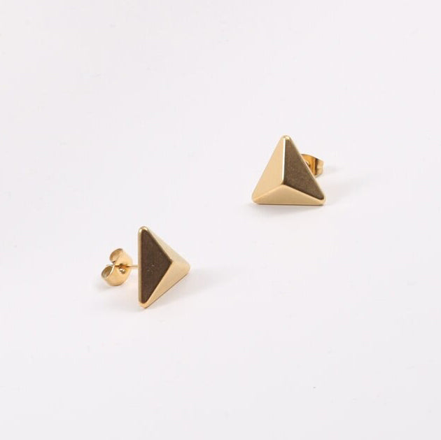 Gold Trigoni Polygon Earrings laying on a smooth white surface.