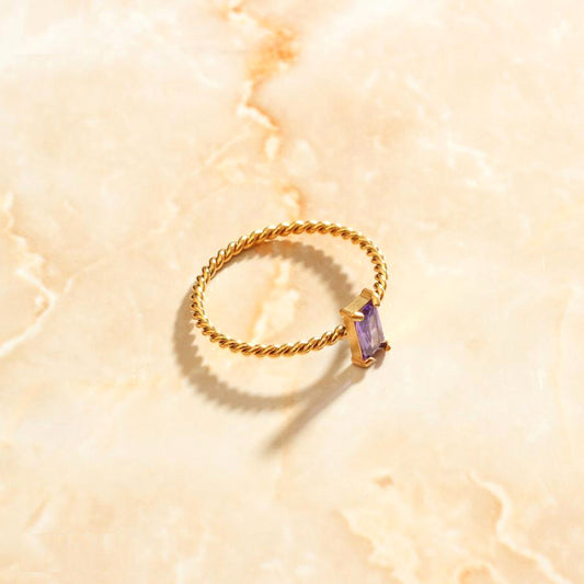 A Gold Twist Cubic Zirconia Ring sitting atop a beautiful quartz surface.