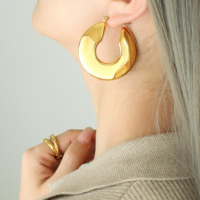Gold Wide Polished Hoop Earrings being worn by a woman with blonde hair.