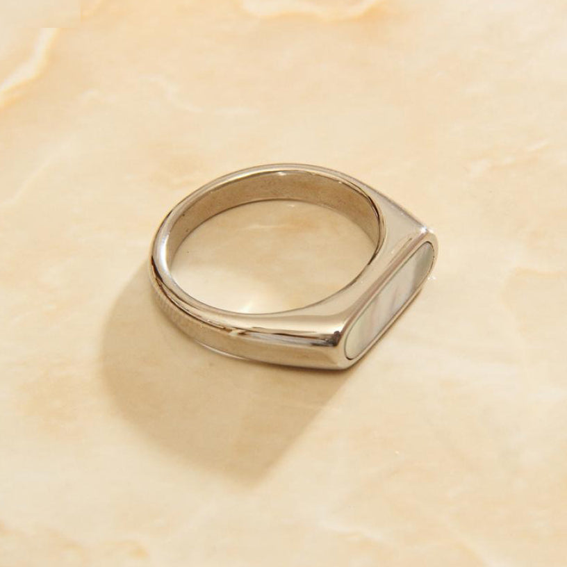 Steel long set signet ring on a smooth marble surface.